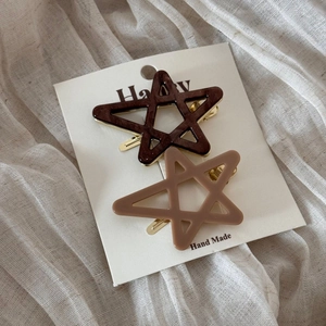 Detail of star-shaped acetate hair clips in coffee and beige on white display card
