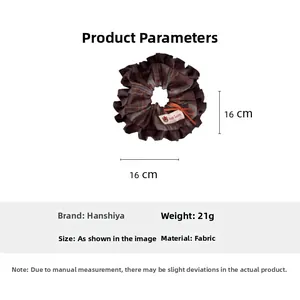 Detailed view of brown plaid hair scrunchie with orange bow and Good Luck bear tag