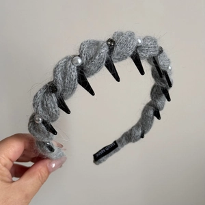 Detailansicht des handgefertigten grauen Strickstirnbands mit Perlen und schwarzen Spikes