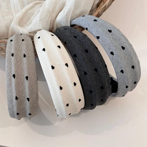 Close-up of four padded velvet headbands with heart embroidery in soft neutral tones