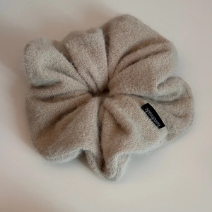 Gros plan du chouchou en maille pelucheuse beige avec détail d'étiquette faite main