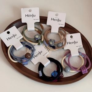 Dettaglio del set di elastici con perline geometriche su vassoio in legno scuro elegante