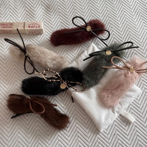 Flat lay of six colorful plush faux fur hair clips with leather bows and gold charms