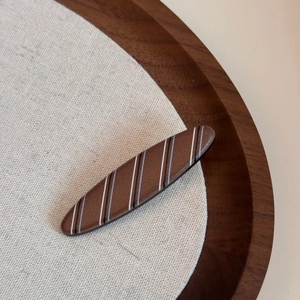 Detail of a brown striped claw clip with fine metallic glitter on a textured surface