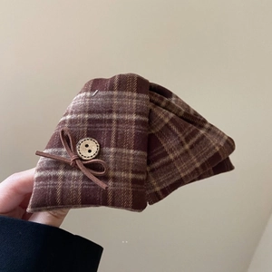 Detail of vintage brown plaid fabric bow hair claw with button accent and tweed texture
