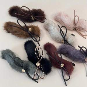 Flat lay of colorful plush bow hair clips with faux fur texture and gold metal tags