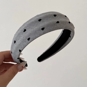 Close-up of light grey flocked headband with black heart patterns and non-slip inner lining