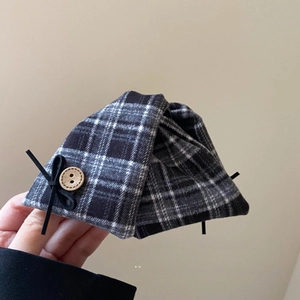 Detail of plaid fabric hair claw with wooden button and black ribbon bow accent