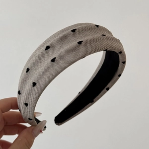 Detailed texture of knitted headband with black heart patterns in beige velvet fabric