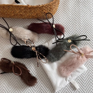Detailed view of plush faux fur hair clips with gold metal tags in various winter colors