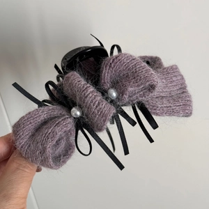 Detail der lila gestrickten Schleifen-Haarklammer mit Perlen und schwarzem Band für Damen