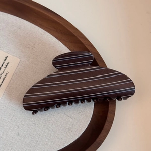 Detail of large brown striped shark hair claw clip on aesthetic wooden tray