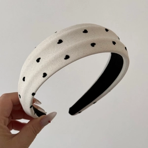 Close-up of thick white velvet headband with black heart embroidery and non-slip lining