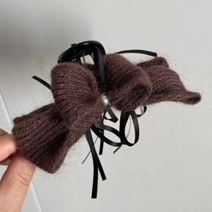 Detail der Strickschleife Haarklammer aus dunkelbraunem Garn mit schwarzen Bändern und Perle