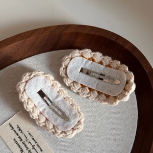 Detail of cute knitted hair clips with cream wool yarn and metal duckbill clip back