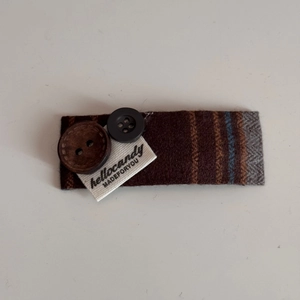 Detail of fabric bow hair clip featuring brown stripes, herringbone pattern, and buttons