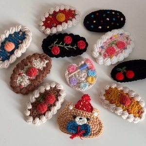 Detailed close-up of handmade crochet hair clips in cute bear and colorful pattern shapes