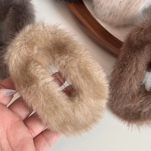 Detailaufnahme weicher Plüsch-Haargummis in neutralen Beige- und Brauntönen für den Winter