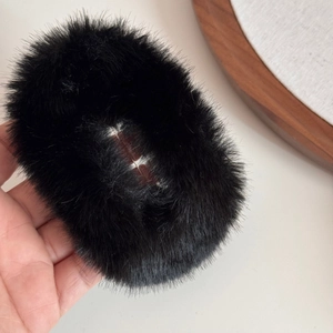 Detail eines weichen schwarzen Kunstfell-Haarrings mit flauschiger Textur im Nahaufnahme