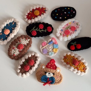 Close-up of handmade crochet hair clips featuring cute bear, cherry, and floral designs