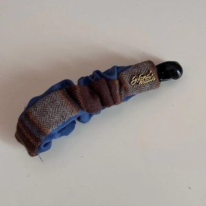 Detail of banana clip with navy pleated fabric and brown herringbone tweed texture