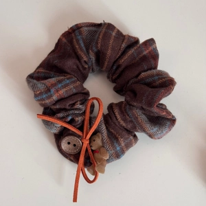 Detail of retro plaid hair tie with orange bow, wooden button and small bear charm