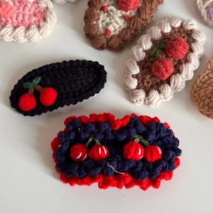 Detailed view of hand-knitted hair clips with cute crochet cherry and wavy edge designs
