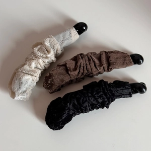 Vue détaillée de trois barrettes banane en velours en couleurs beige, marron et noire