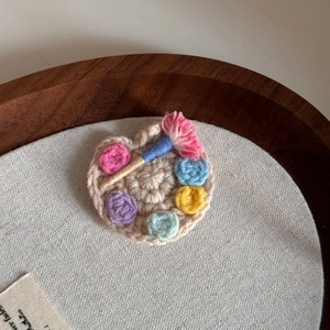 Macro shot of handcrafted crochet painter's palette hair clip with colorful wool details
