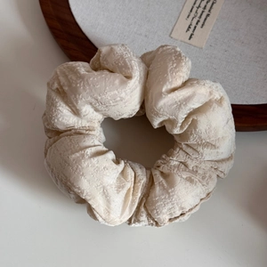 Gros plan d'une pince à cheveux crème montrant la texture du tissu et le style rétro