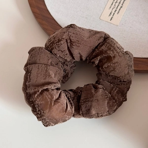 Gros plan sur une grande pince banane en velours marron foncé avec plis rétro chic