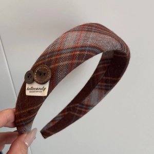 Detail of wide plaid headband in brown vintage fabric with decorative side buttons