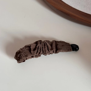 Détail de la pince à cheveux banane vintage en velours marron foncé avec texture plissée