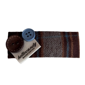 Vintage brown herringbone fabric hair clip with decorative buttons on white background