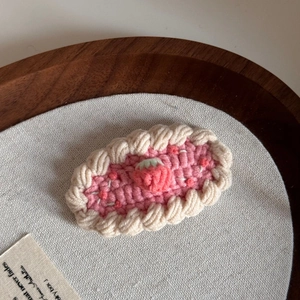 Close-up of handmade pink crochet BB hair clip with cute strawberry detail for kids