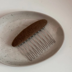 Detail view of brown fabric covered hair comb showing the textured knit and metal teeth