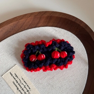 Detailed macro view of handmade crochet cherry hair clips with red and blue knit textures