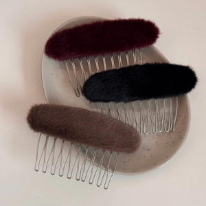 Eleganti pettini ovali in peluche bordeaux, nero e talpa su un piatto di ceramica