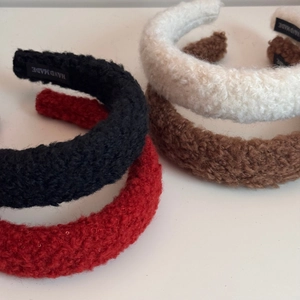 Close-up of thick sherpa fleece headbands with handmade woven labels in multiple colors