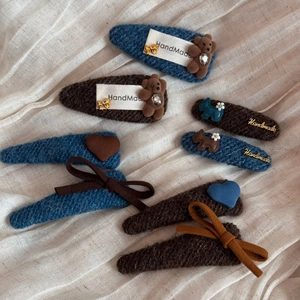 Handgefertigte Stoff-Haarspangen mit Strickbären und Herzen auf Leinenhintergrund