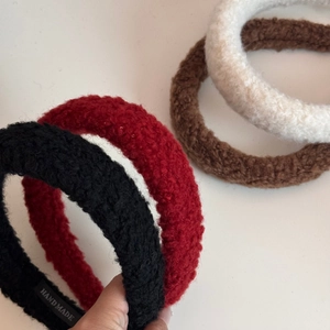 Detail view of four thickened faux shearling headbands with a handmade fabric label