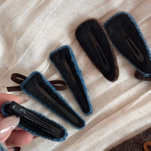 Nahaufnahme von gestrickten Haarklammern mit Filzrücken und schwarzen Metallclips