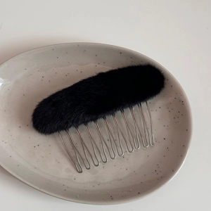 Dettaglio del materiale in peluche nero e dei denti in metallo argentato del pettine