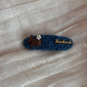 Detail einer dunkelblauen Strick-Haarklammer mit braunem Hund und Goldplakette Handmade