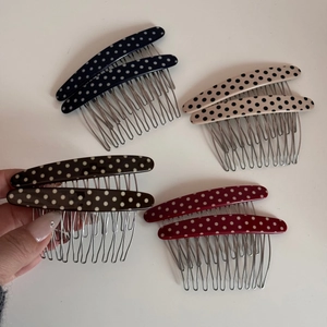 Close-up of four colored polka dot hair combs featuring metal teeth and resin finish