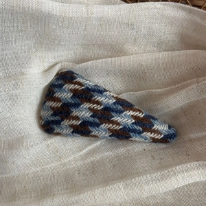 Close-up of vintage blue and brown herringbone fabric texture on a triangular hair clip