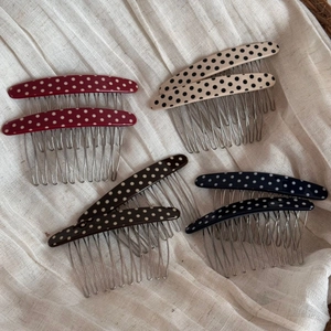 Detailed view of four pairs of polka dot hair side combs on white linen background