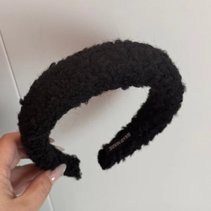 Close-up of black lamb wool headband featuring a handcrafted detail label inside
