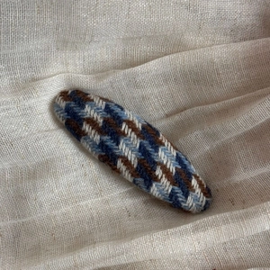 Detail of British style houndstooth fabric triangular hair clip with navy and brown weave