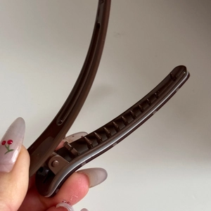 Detail view of brown duckbill hair clip with non-slip teeth and glossy finish